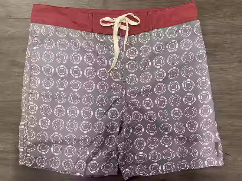 Front view of fixed-waist board shorts with gray circular geometric print
